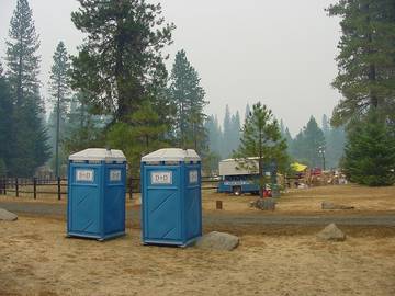 Two portable toilets set up on a dirt lot